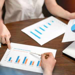 woman-showing-man-finance-diagrams-table-laptop-papers